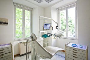 A treatment chair in a dentist's office overlooking a window.